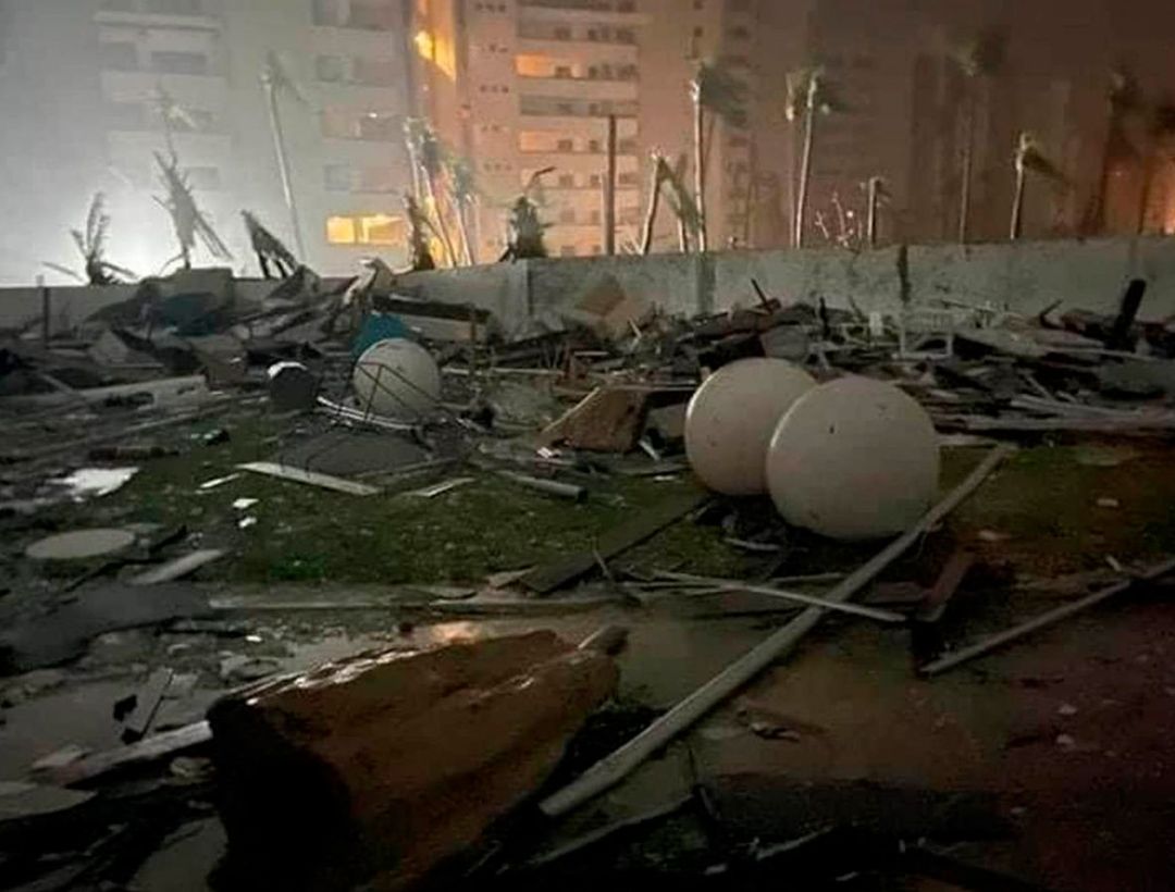 La imagen muestra una escena de destrucción nocturna con escombros y esferas blancas