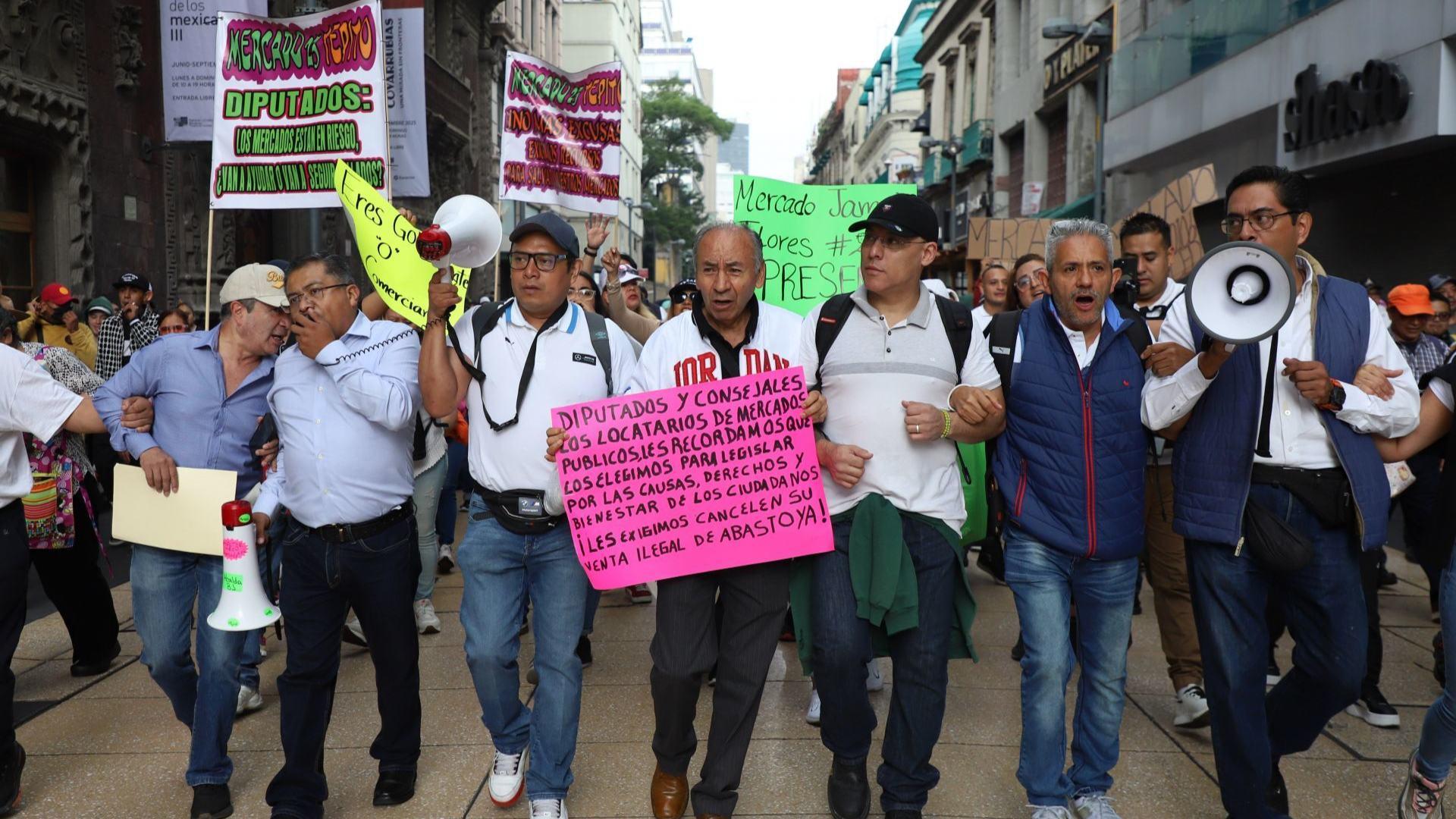 Comerciantes caminan por calles de la CDMX cargando mantas y cartuinas
