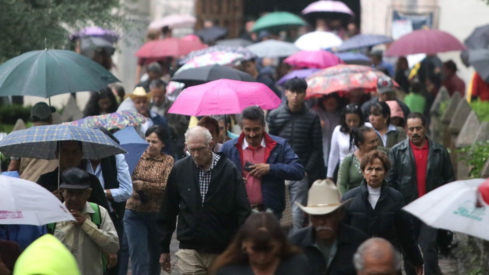 Personas caminan con paraguas y chamarras en calles de la CDMX