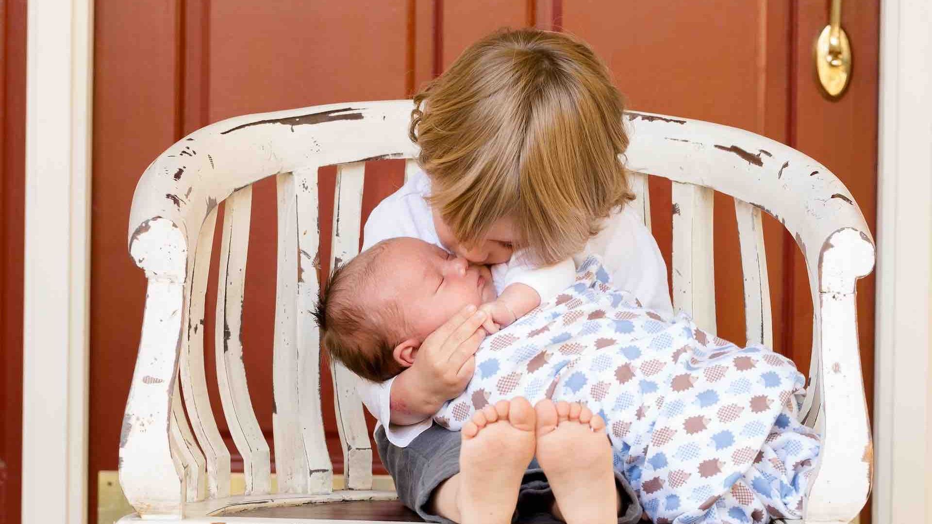 Niño sostiene a un bebé recién nacido