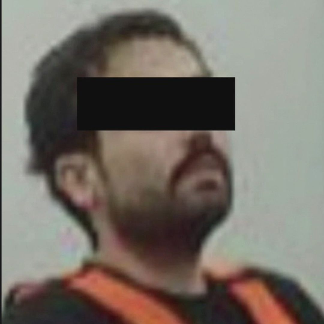 Ovidio Guzmán tras su detención, luce con bigote y barba, una playera negra y una chaleco naranja