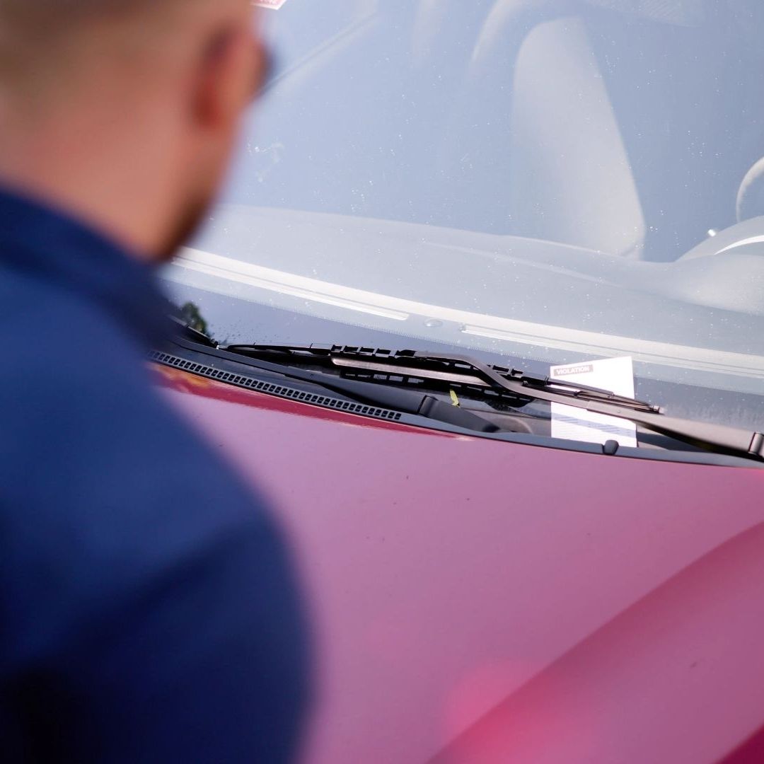 Sad Driver Looking At Parking Ticket On Car