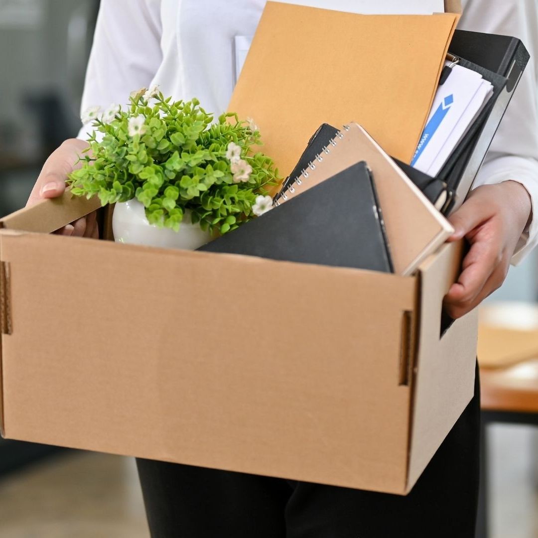 A female office worker with a cardboard box with her stuff and her resignation letter