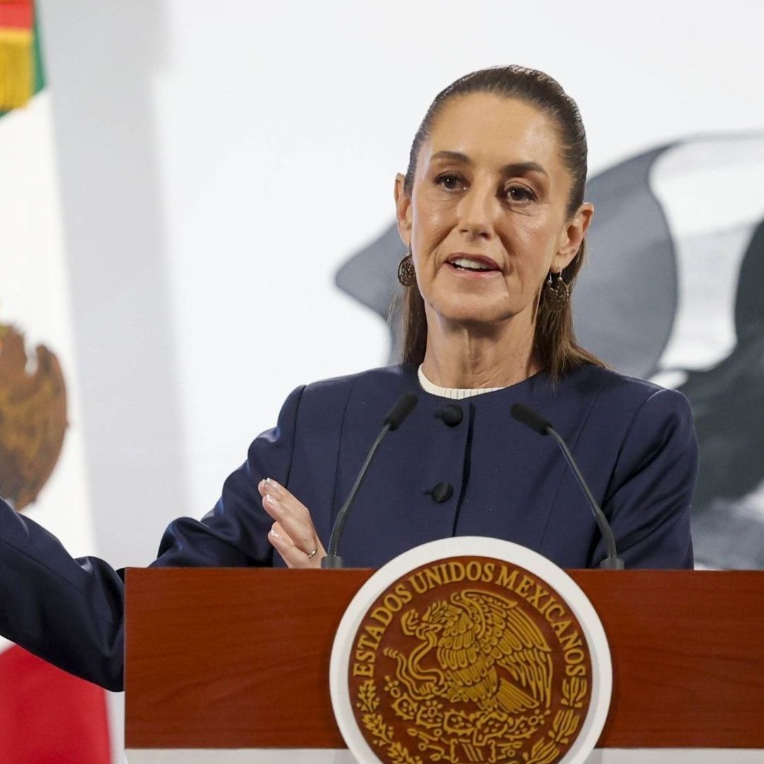 Una mujer al lado de una bandera de México está sonriendo.
