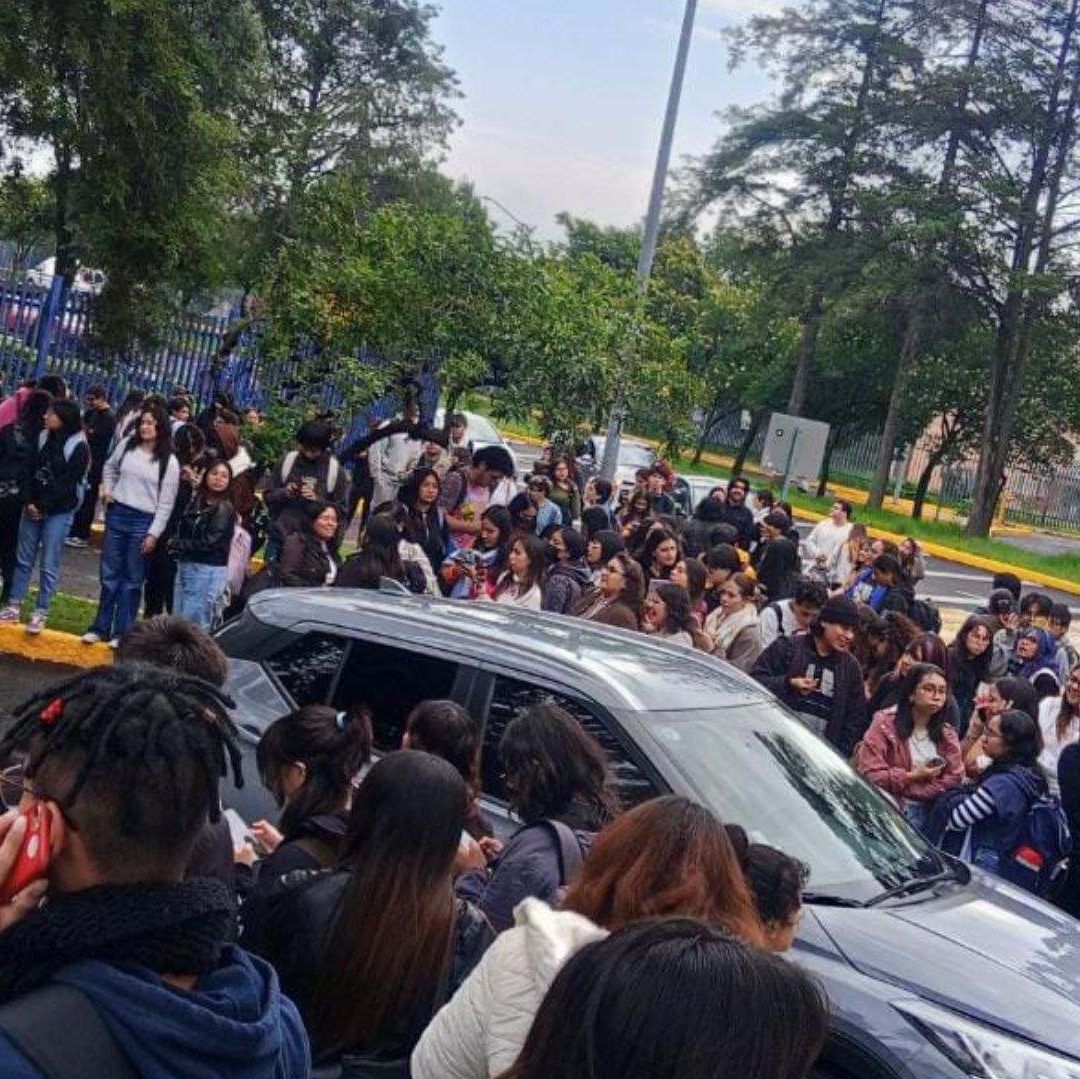Varios estudiantes en un grupo fuera de una escuela.
