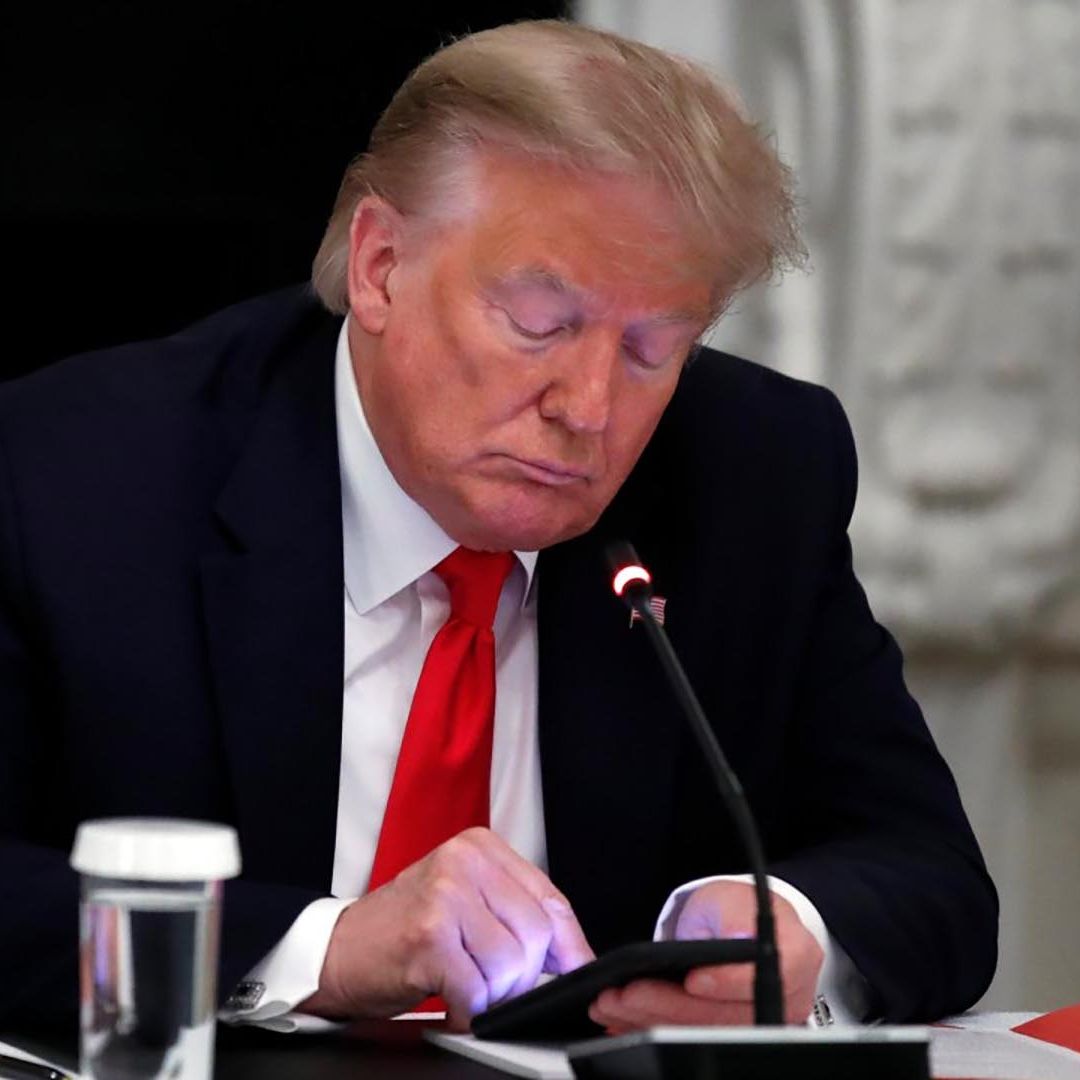 Donald Trump revisa su teléfono durante una pausa en una reunión de trabajo