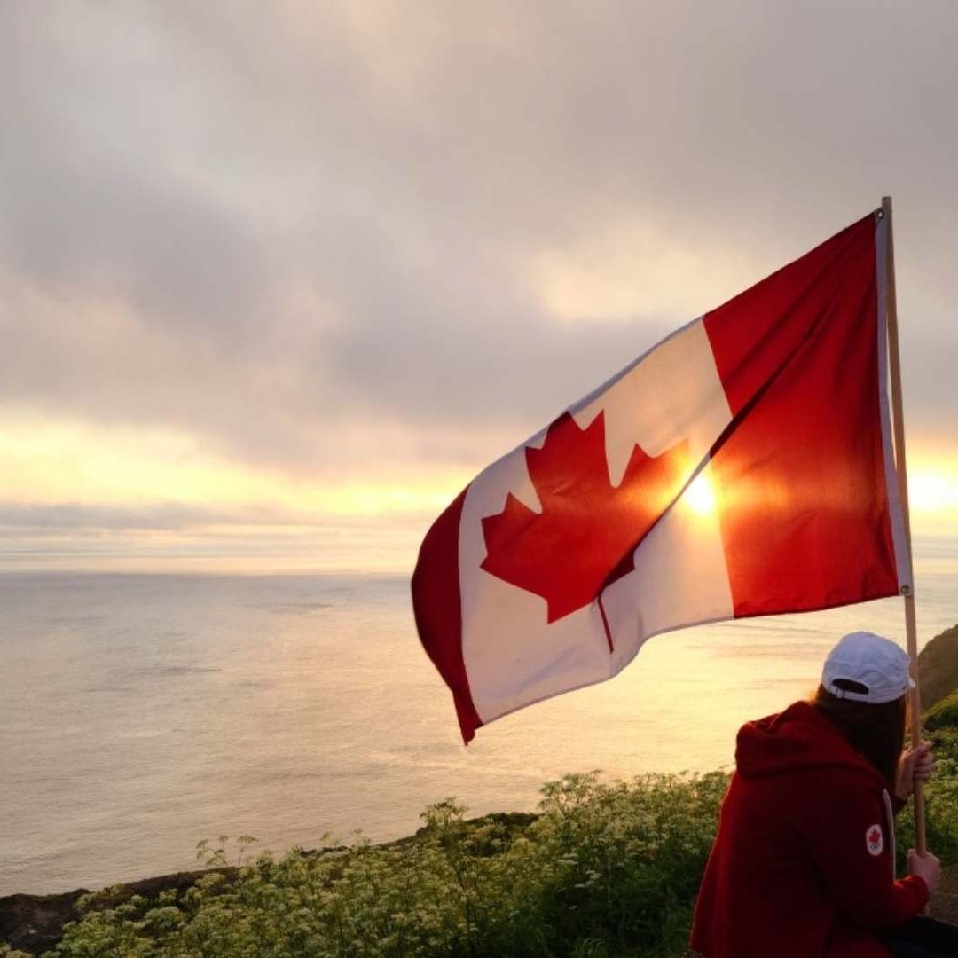 Ondea una bandera de Canadá mientras una joven observa el horizonte