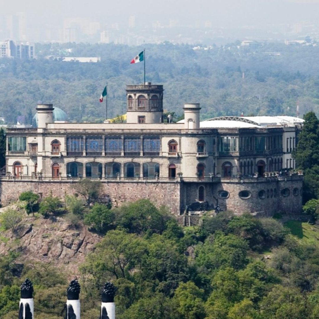 Un edifico histórico de gran tamaño, rodeado de áreas verdes.