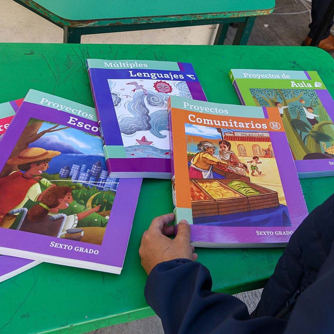 Libros de texto gratuito sobre una mesa verde en escuela de Edomex