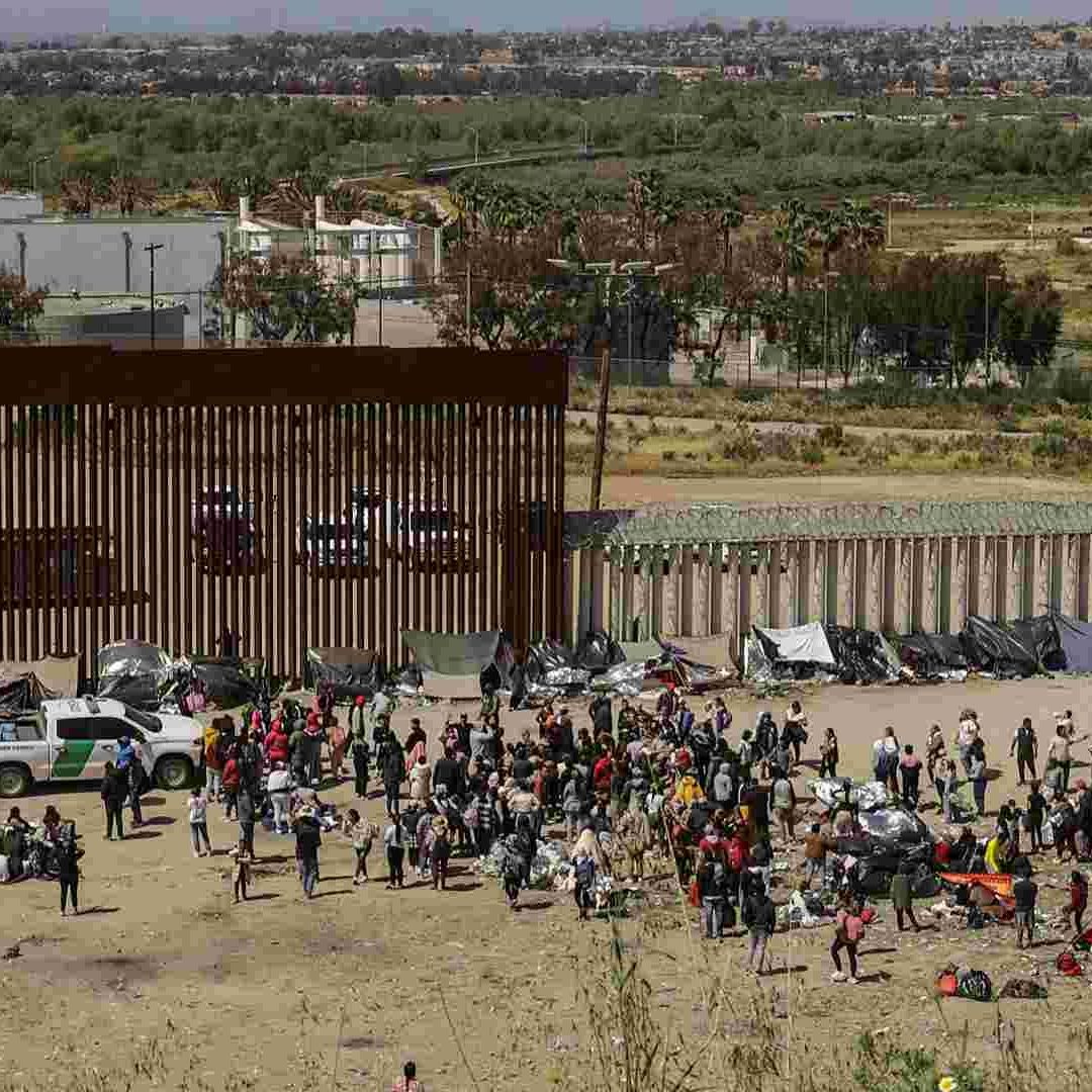 migrantes en un campamento junto al muro fronterizo