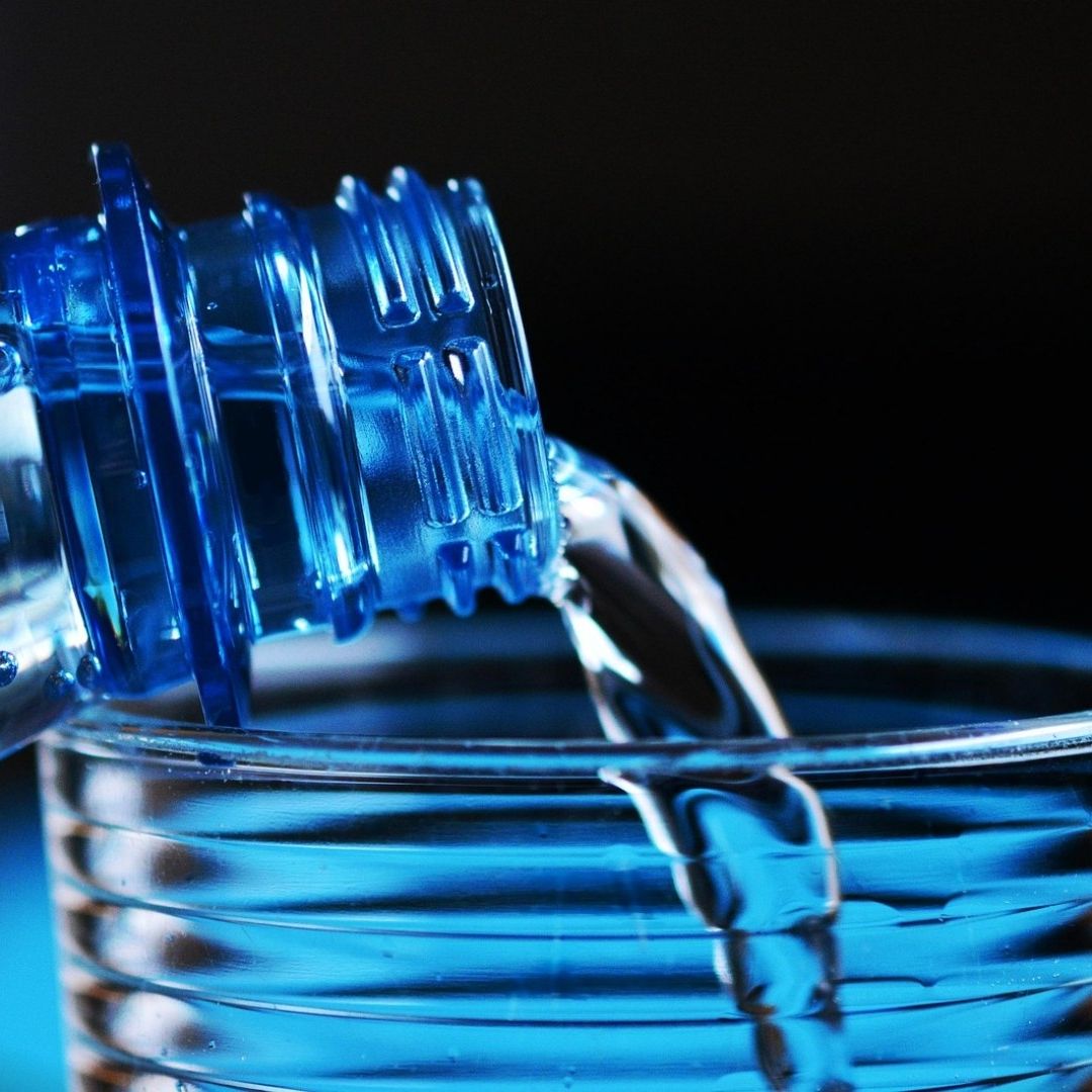 botella de agua simple con un vaso de vidrio