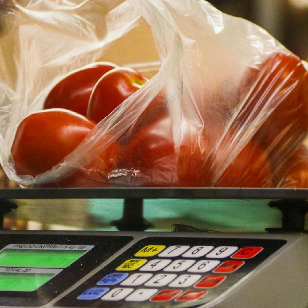 un vendedor pesa en una báscula una bolsa con jitomates