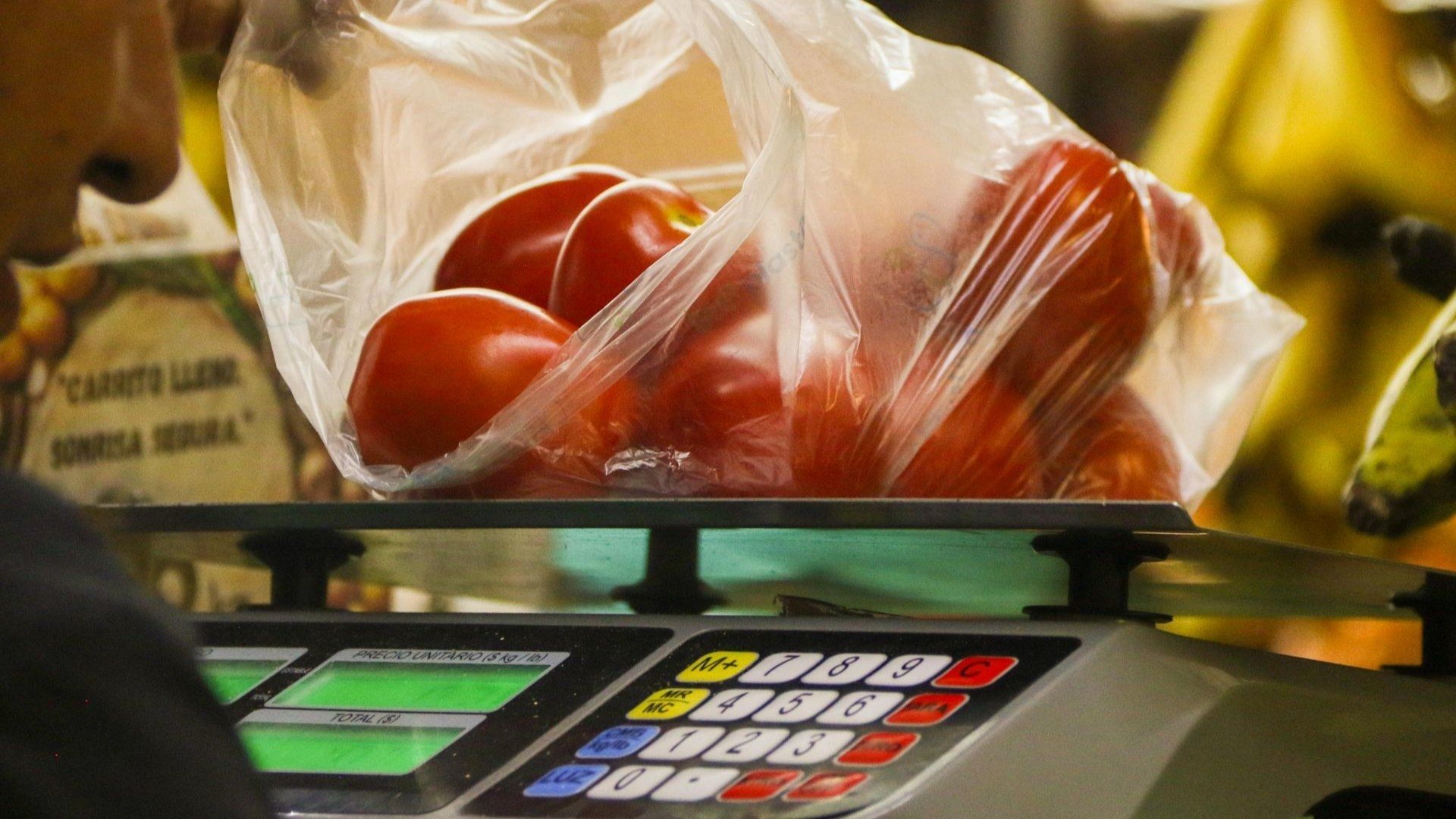 un vendedor pesa en una báscula una bolsa con jitomates