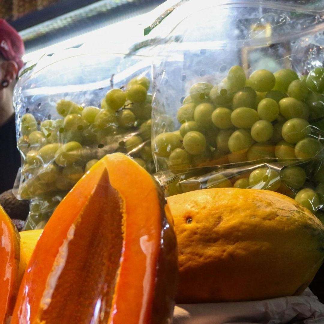 vendedor junto a papayas y uvas