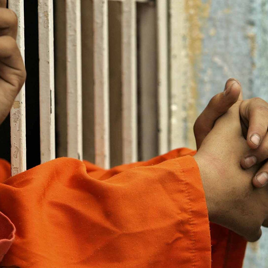 Jóvenes recargan sus brazos en barrotes de prisión en Irak, 2004