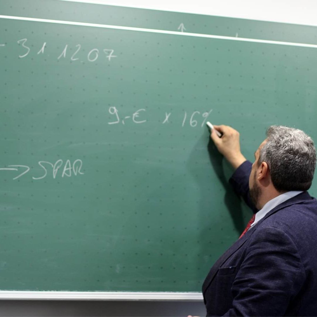 Un profesor escribe sobre un pizarrón