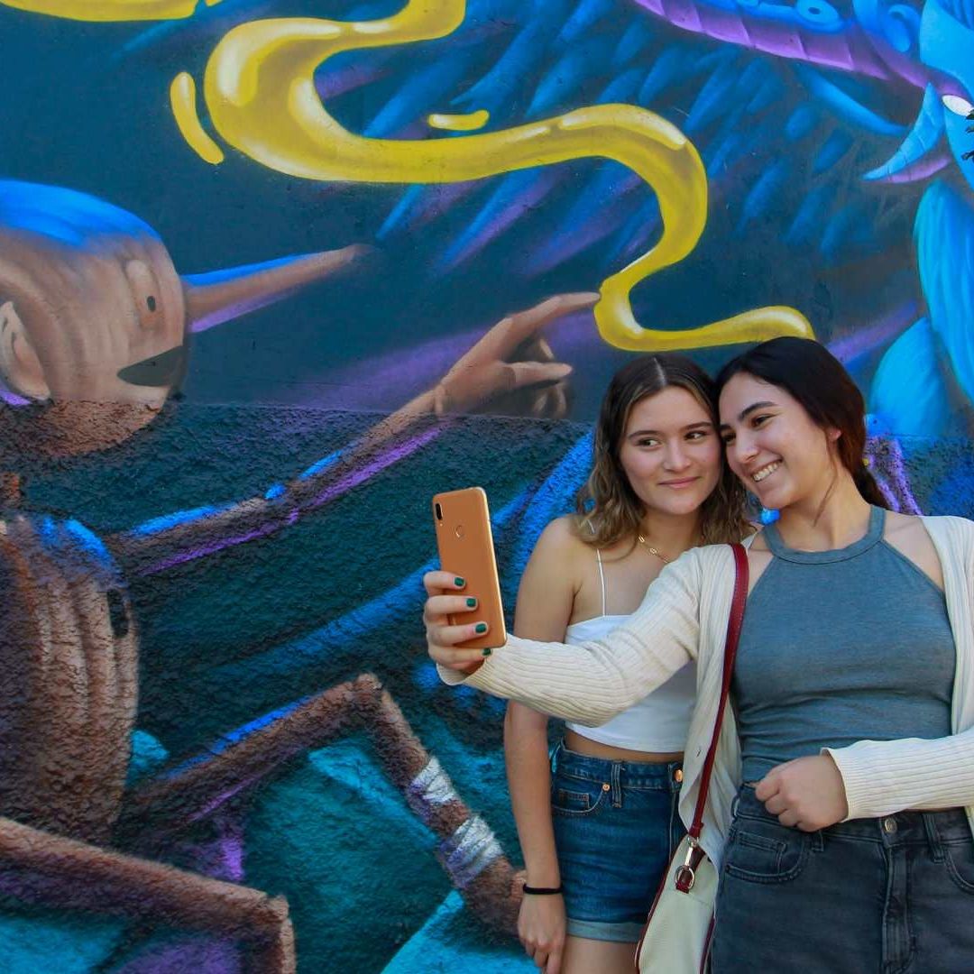 Dos mujeres se toman una foto junto a un mural inspirado en la película "Pinocchio" del cineasta mexicano Guillermo del Toro