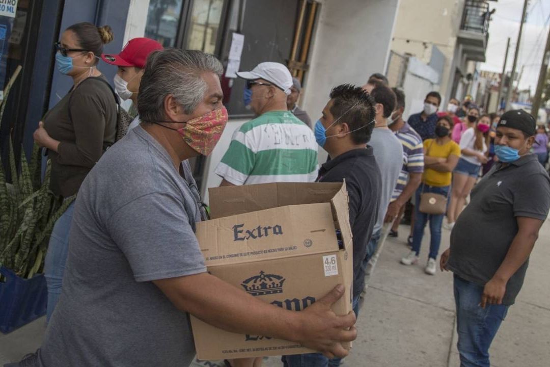 Un hombre compra un cartón de cerveza de una tienda de autoservicio