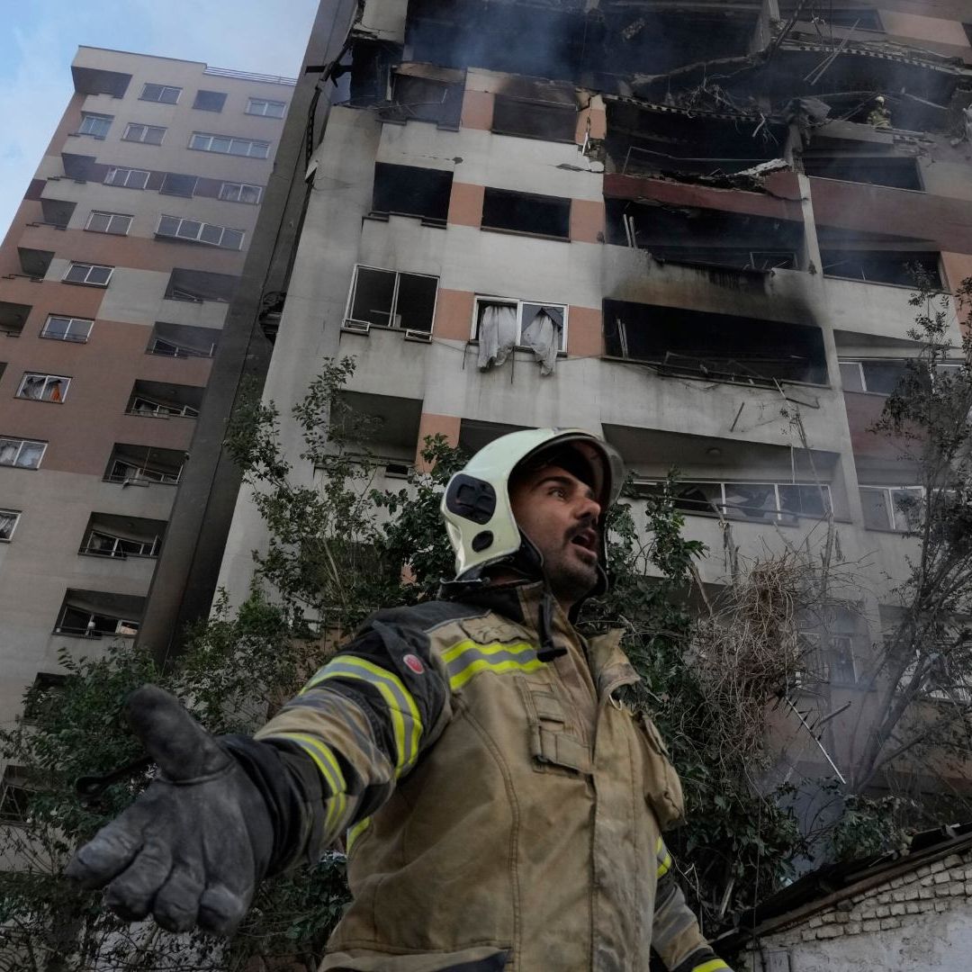Un bomber con un edificio destruido al fondo luego de explosión