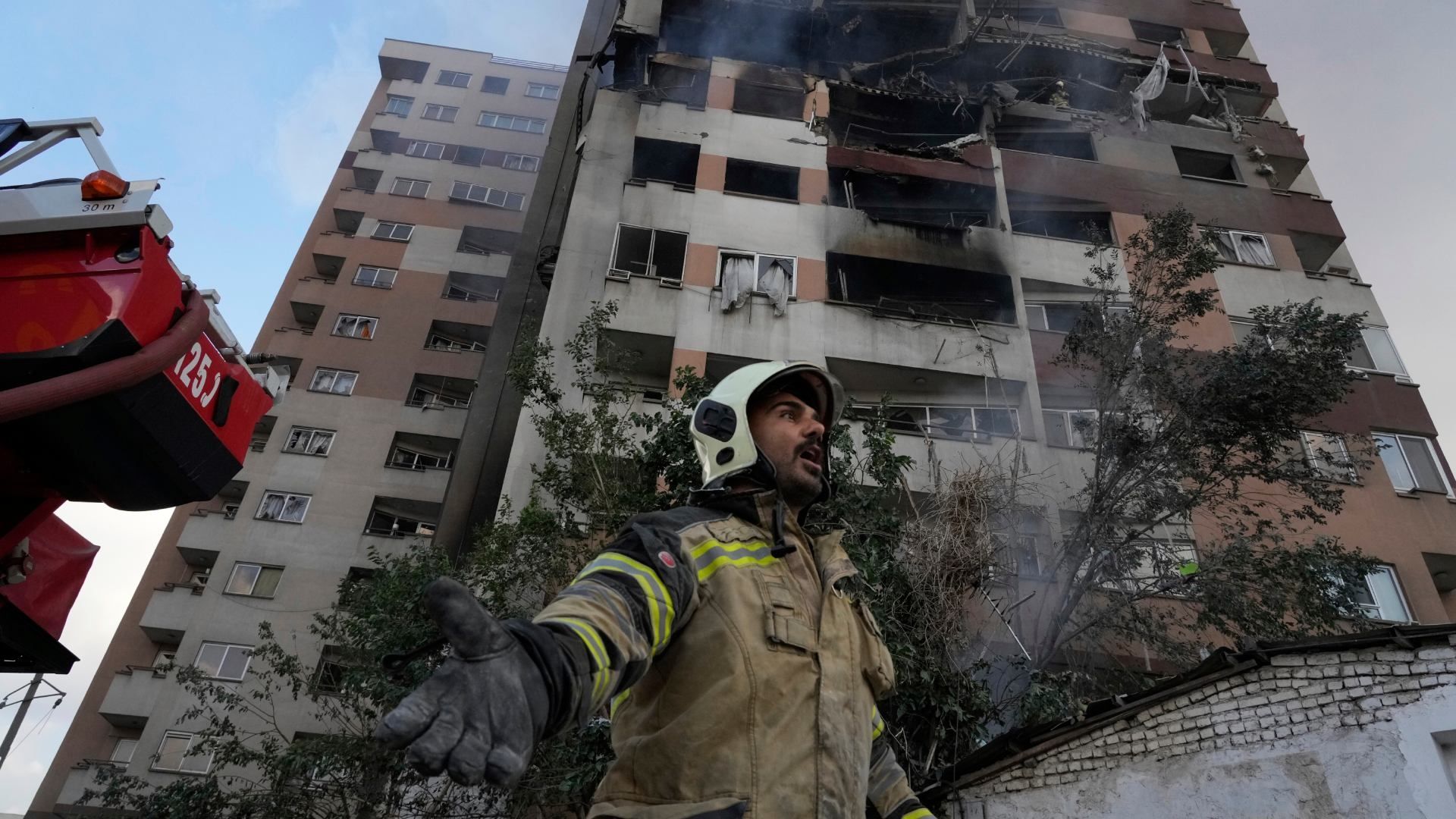 Un bomber con un edificio destruido al fondo luego de explosión