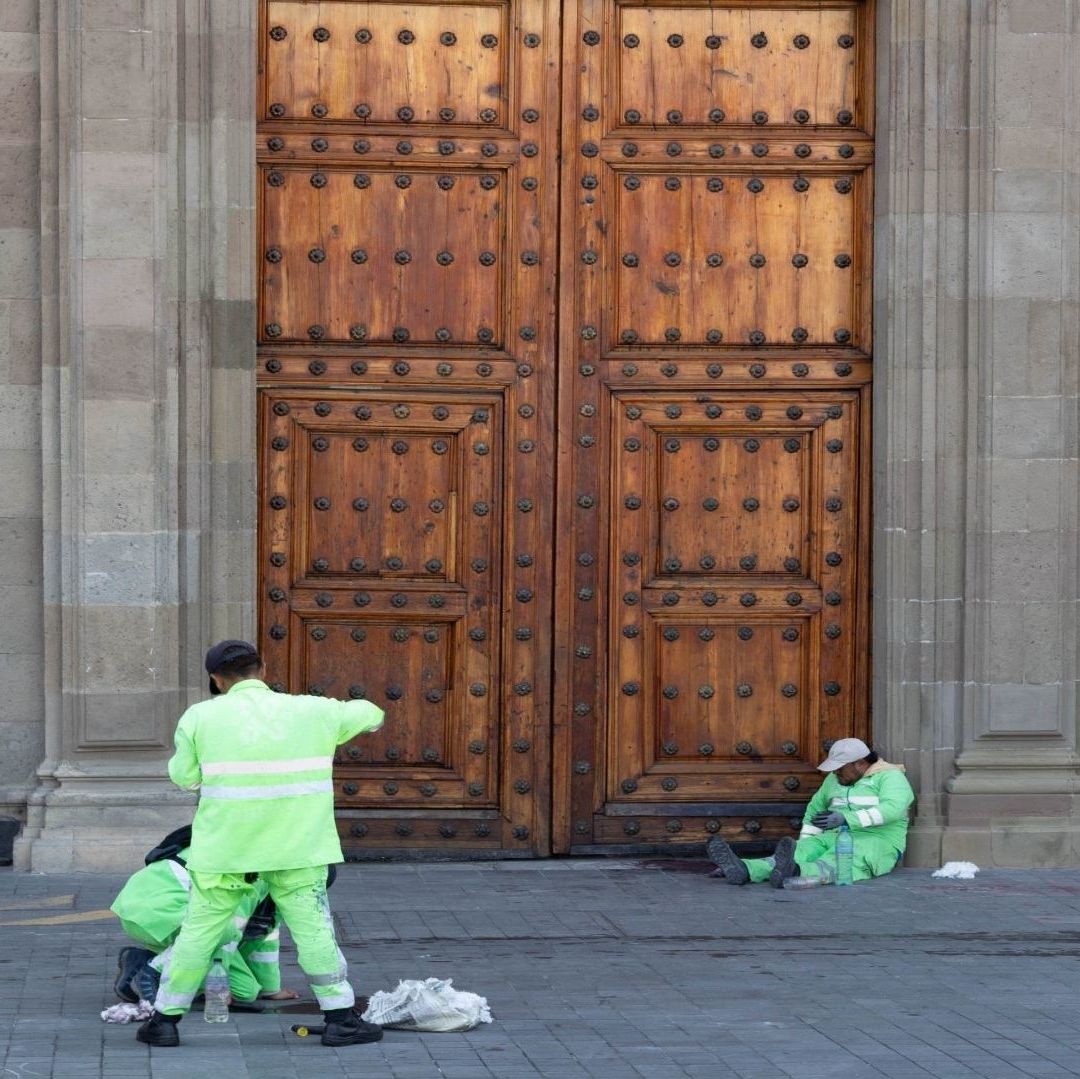 Trabajadores de limpieza usan un traje verde fosforescente; realizan sus labores.