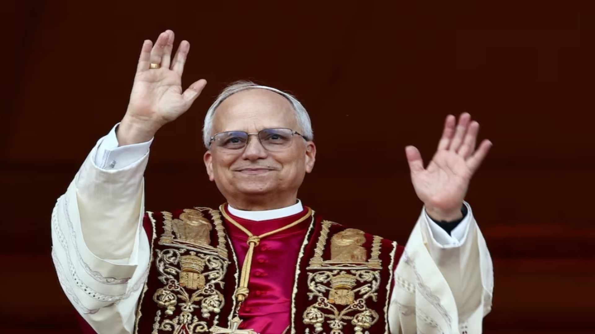 El Papa León extendiendo las manos, usa unos lentes y ropa blanca.