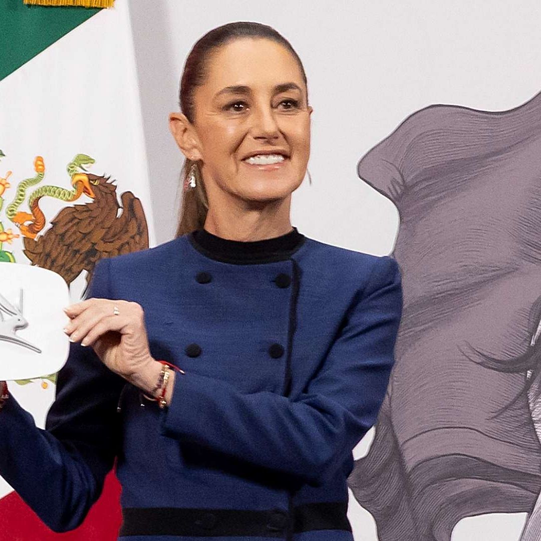 La presidenta Claudia Sheinbaum muestra el emblema del auto eléctrico Olinia durante su conferencia mañanera