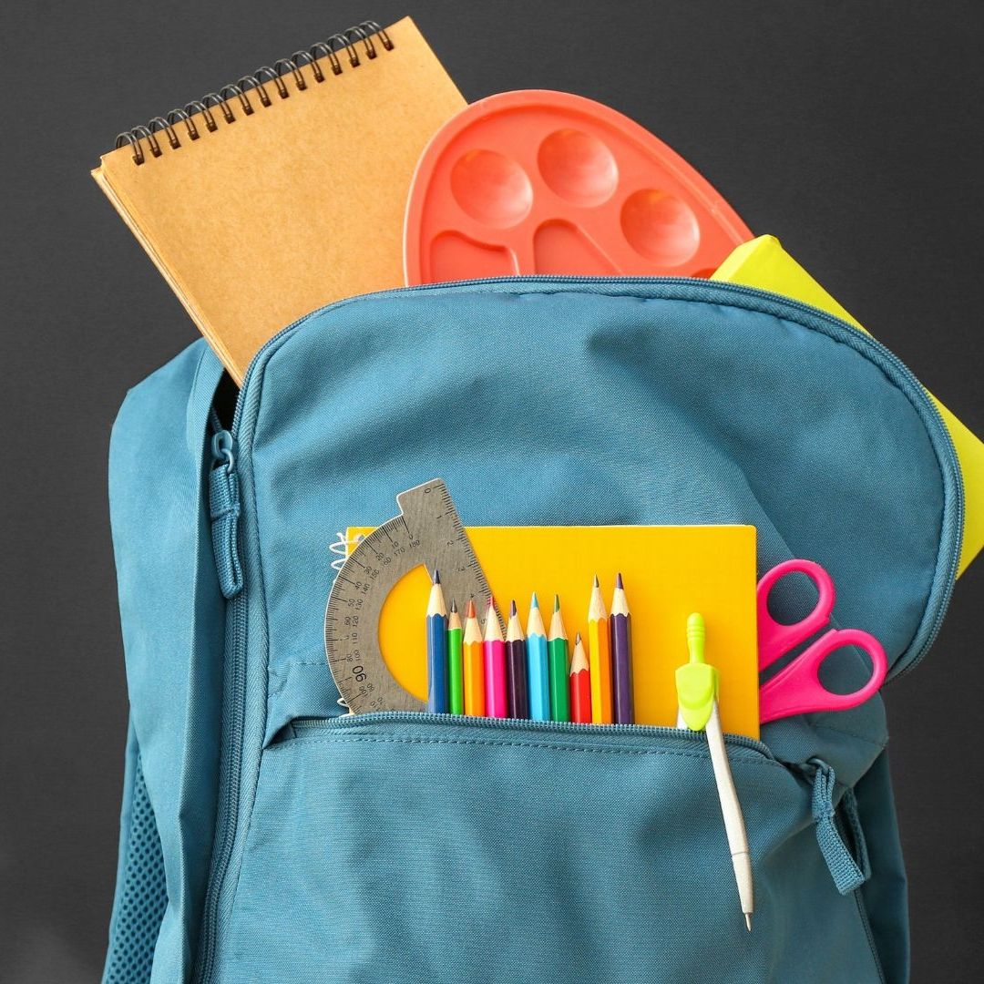 Mochila con útiles escolares como colores, libretas y tijeras