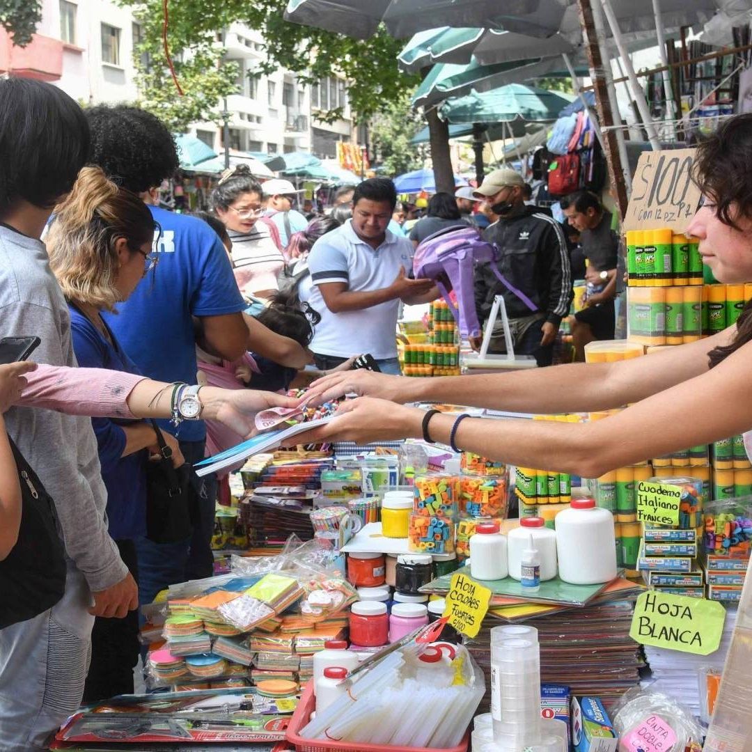 Personas comprando en un local de útiles escolares, una de ellas está pagando.