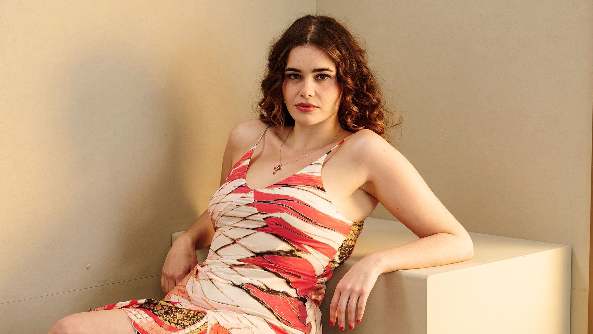 Barbie Ferreira recargada en un cubo con un fondo color beige.