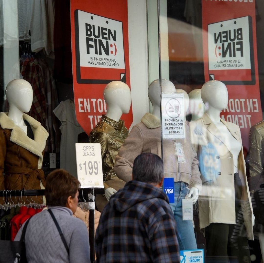 Dos adultos mayores afuera de una tienda de ropa.