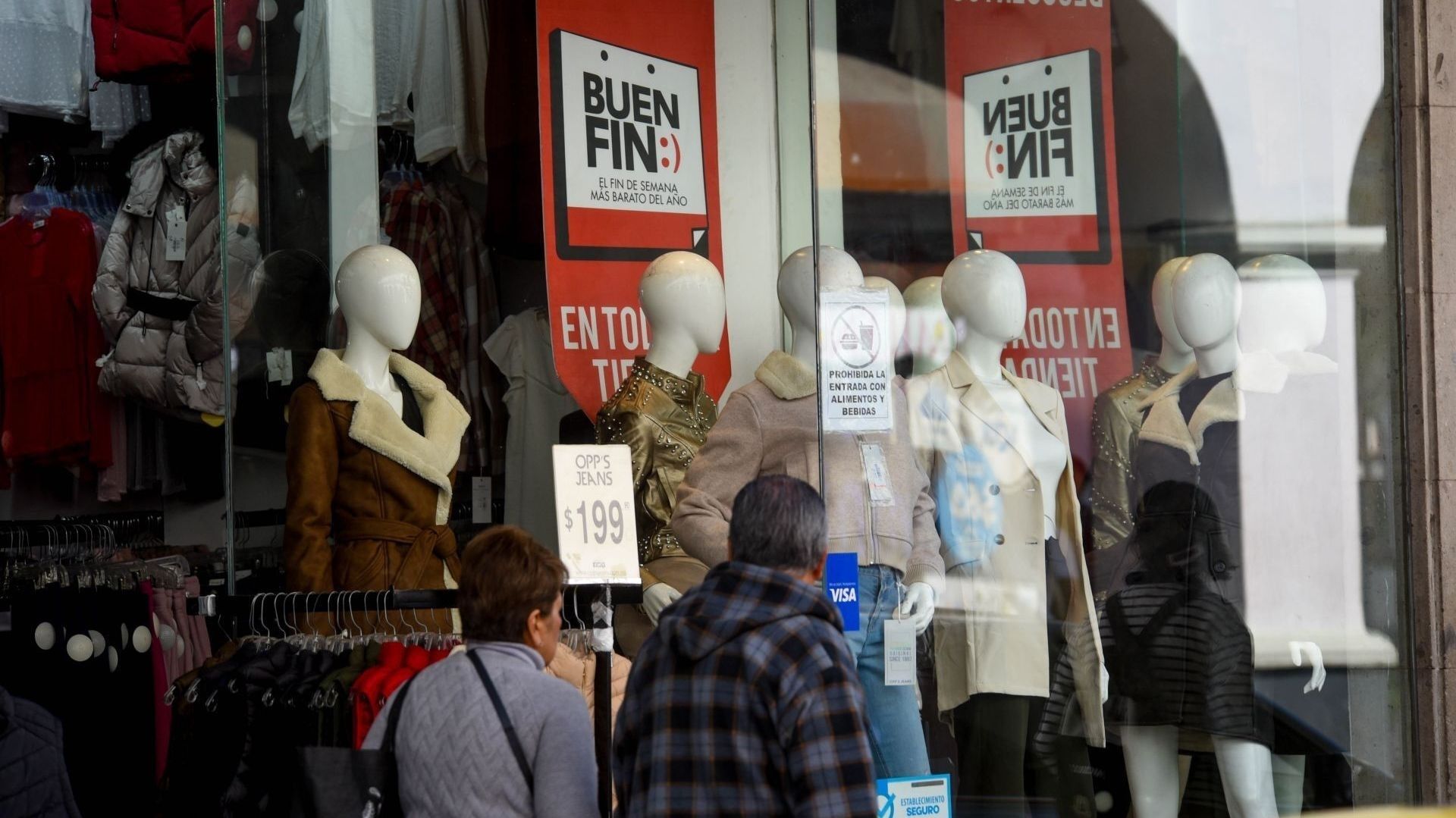 Dos adultos mayores afuera de una tienda de ropa.