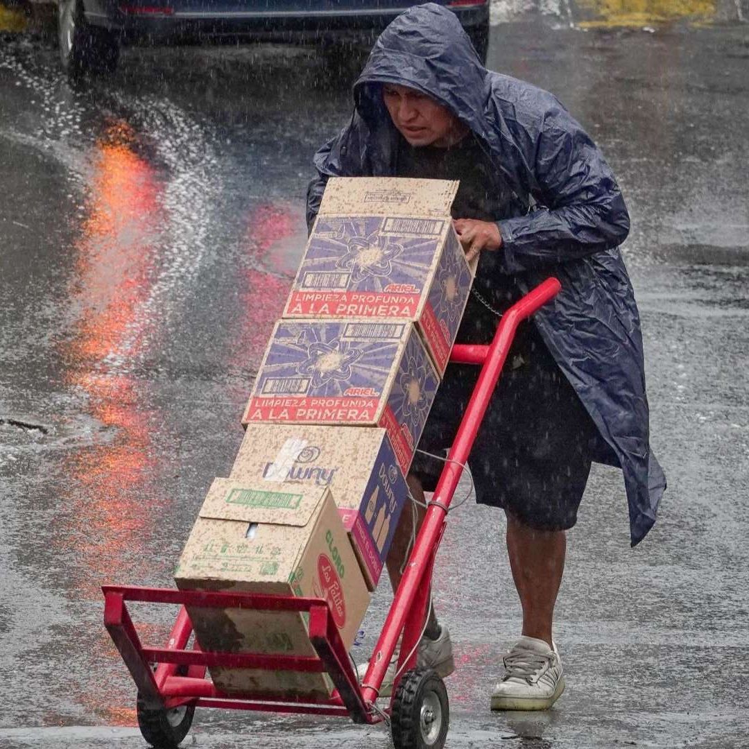 Persona empuja un diablito bajo la lluvia en CDMX