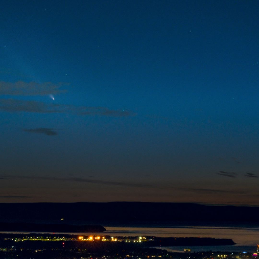 Vista nocturna del horizonte con un cometa surcando el cielo azul oscuro sobre un paisaje urbano. Anchorage, Alaska