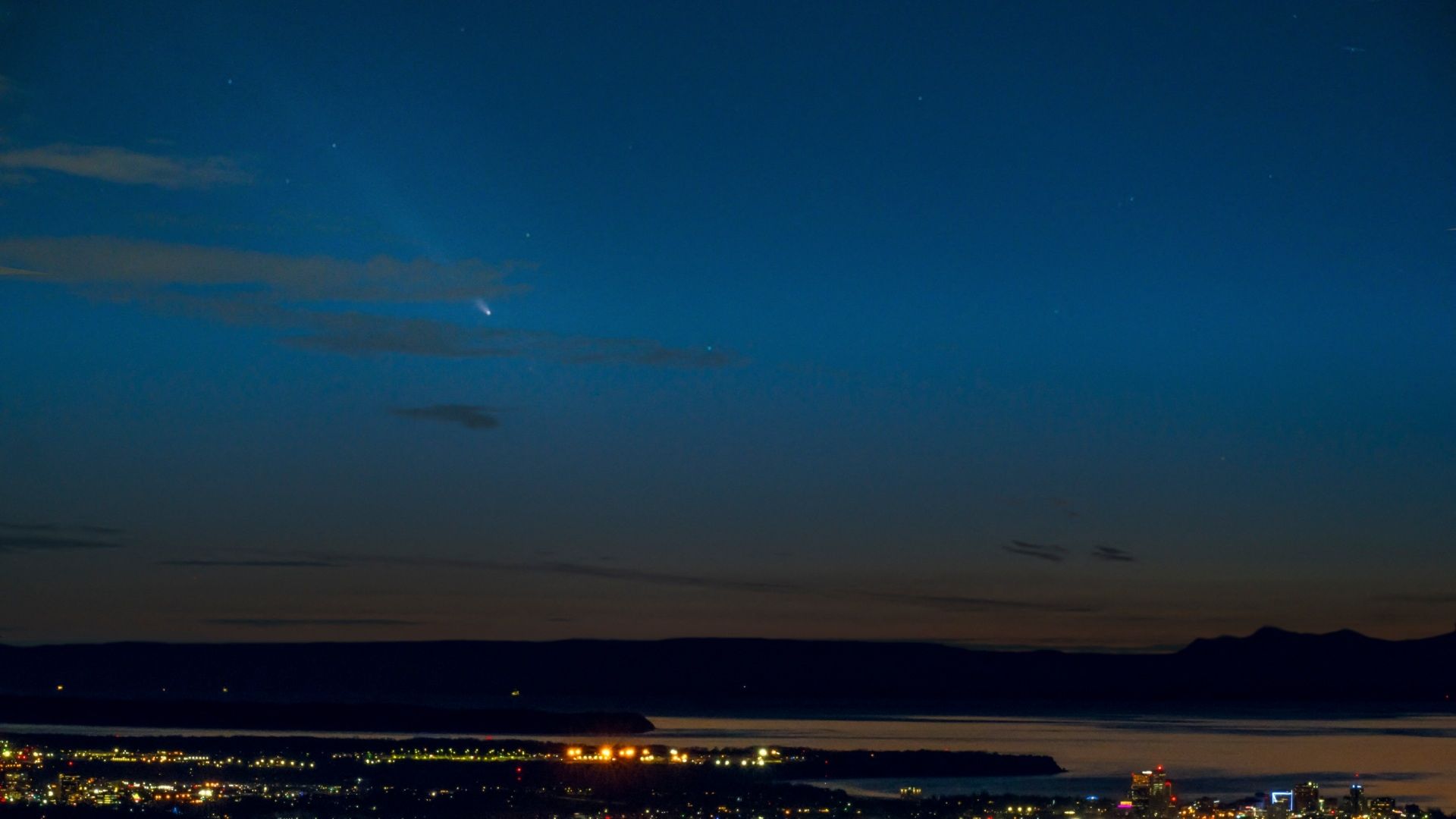 Vista nocturna del horizonte con un cometa surcando el cielo azul oscuro sobre un paisaje urbano. Anchorage, Alaska