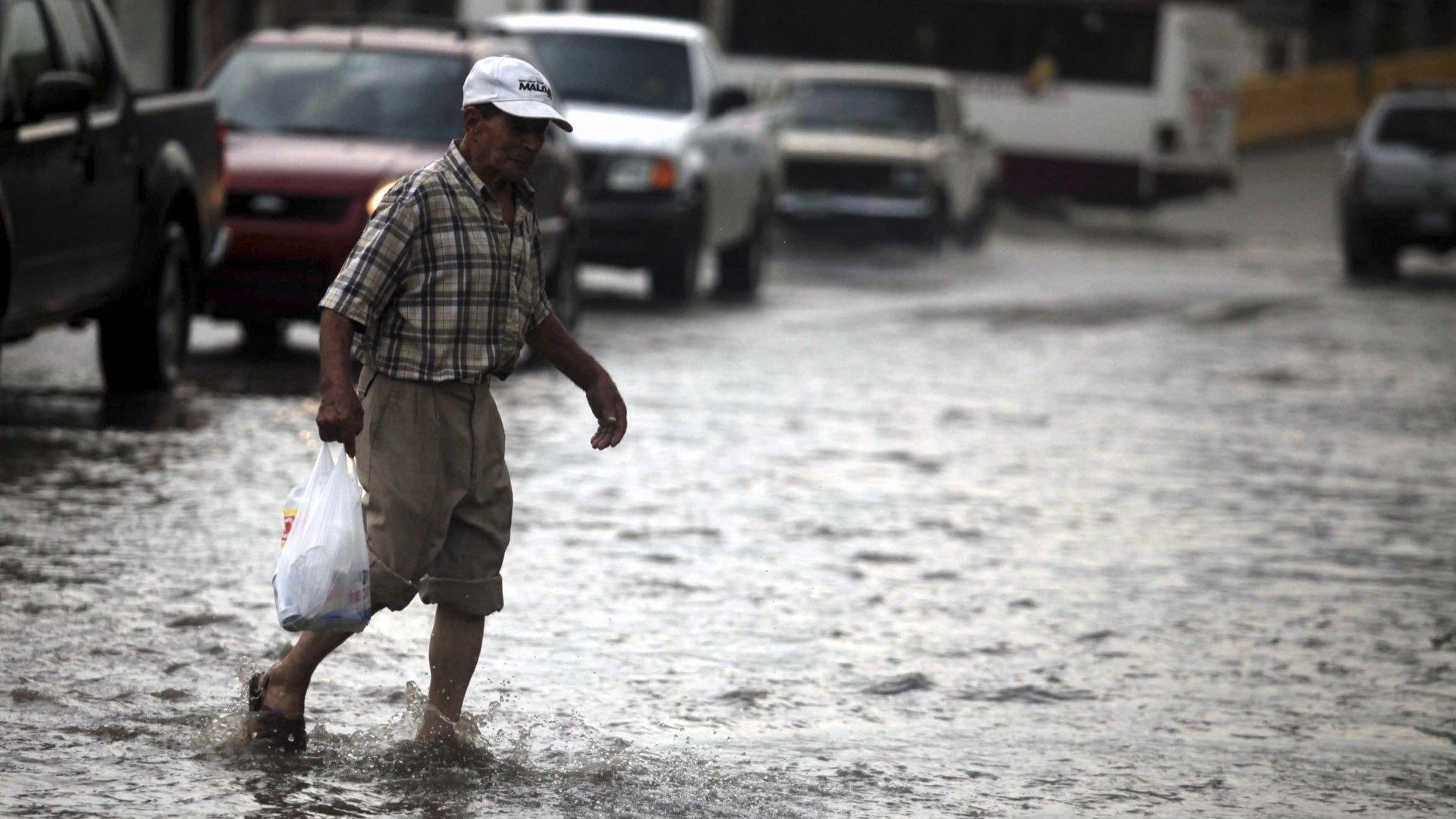 Una persona camina rápido bajo la lluvia.