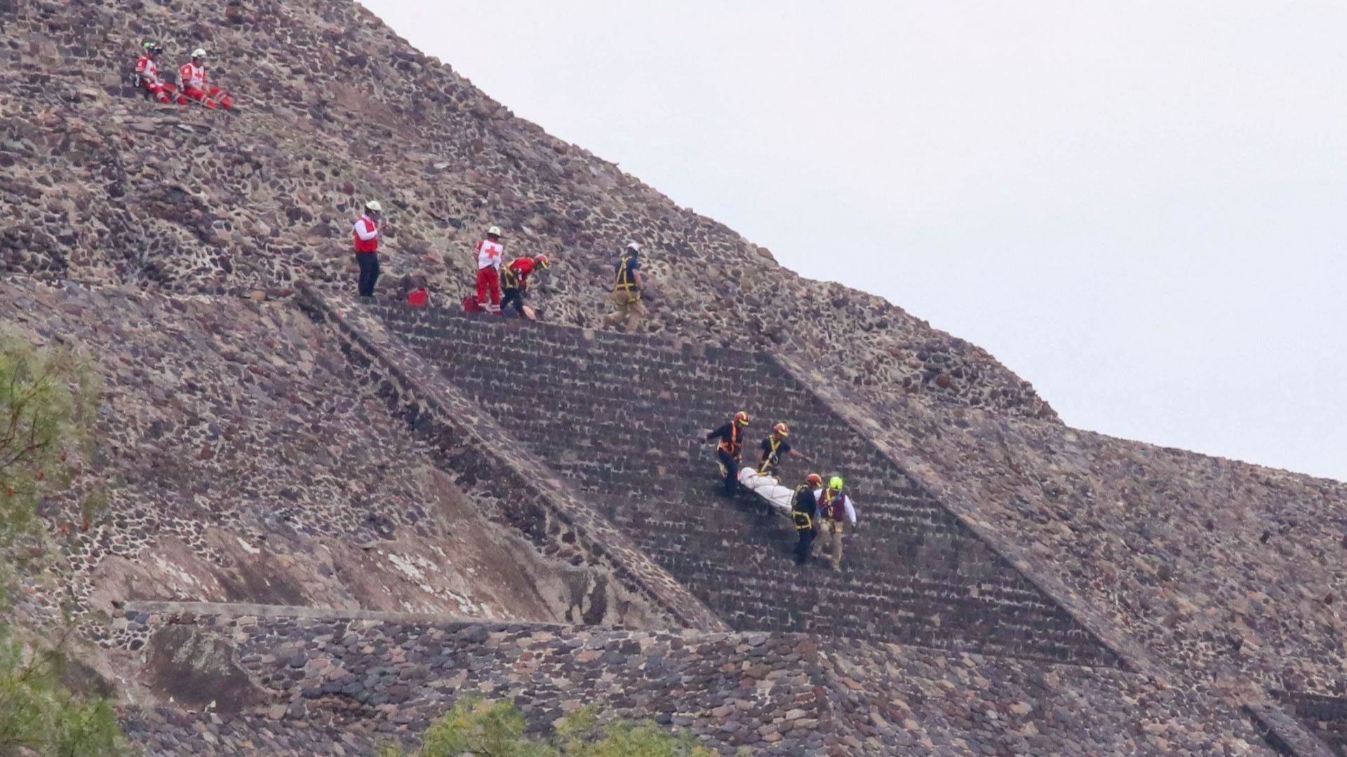 paramédicos descienden de pirámide con persona muerta