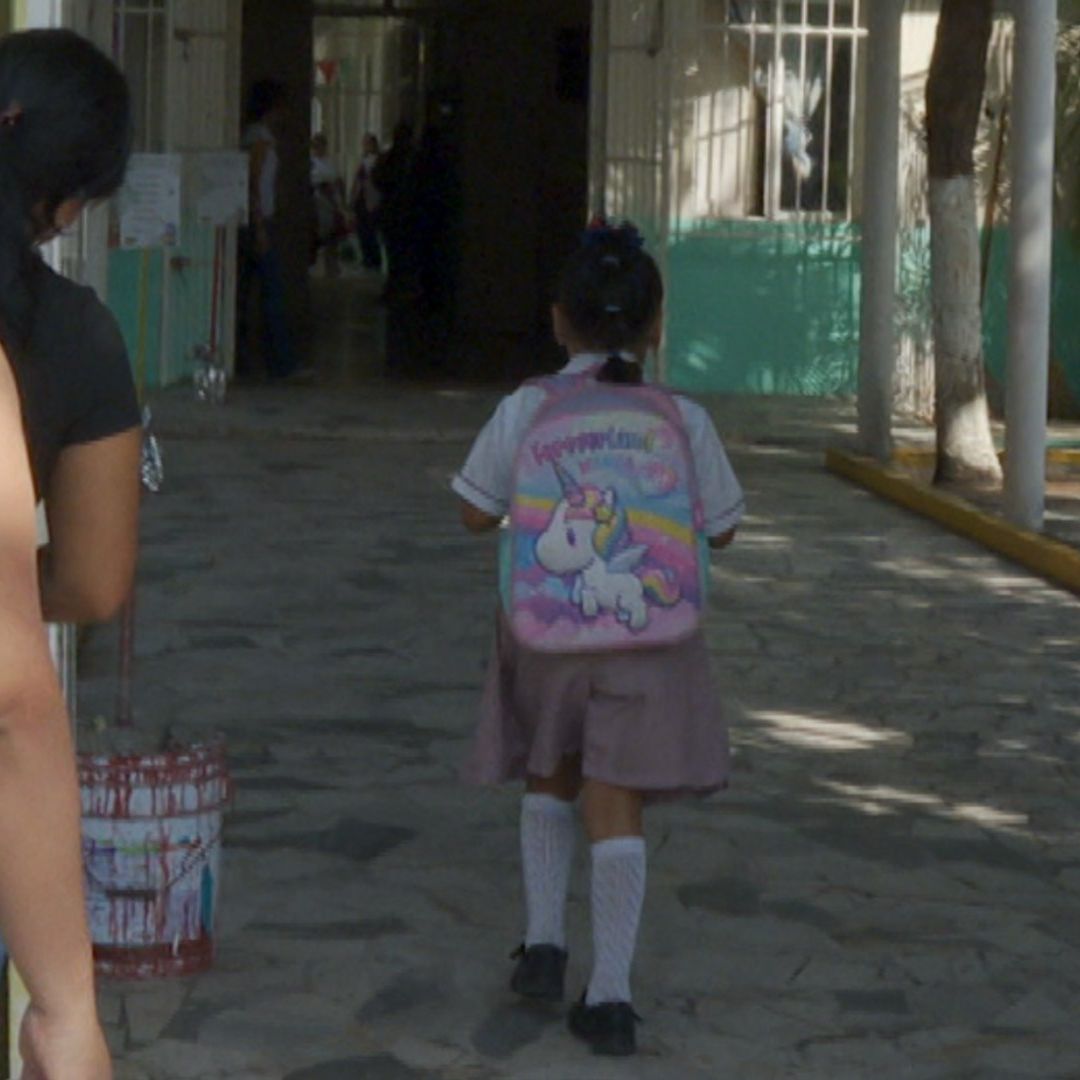 Menor estudiante de preescolar caminando hacia su salón de clases