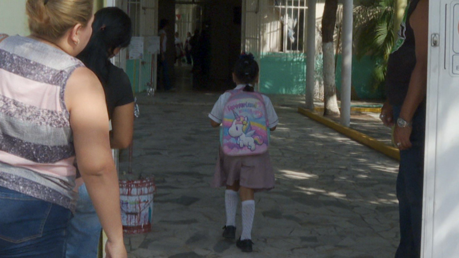 Menor estudiante de preescolar caminando hacia su salón de clases