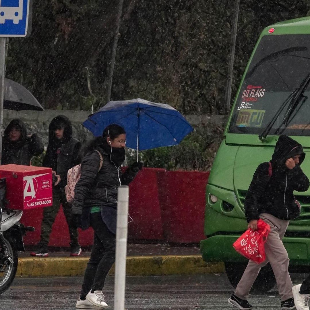 Personas cruzan a calle en medio de la lluvia.