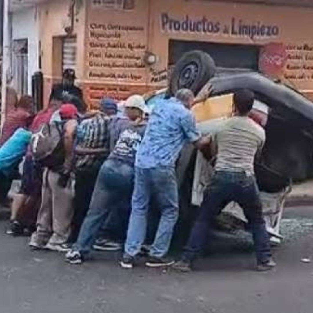 personas ayudando a voltear taxi volcado en Córdoba.