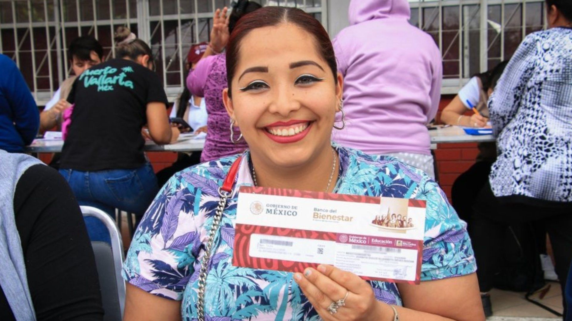 Mujer sostiene una Tarjeta del Bienestar. Qué documentos piden a papás para recoger Tarjeta de la Beca