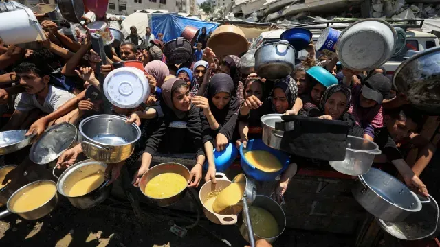 Palestinos con cacerolas intentan llevar algo de comer a sus familias. Foto: Reuters