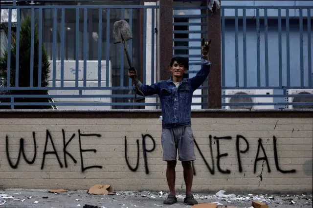 Manifestante tras una protesta en Katmandú; detrás una pinta reza ‘Despierta, Nepal’