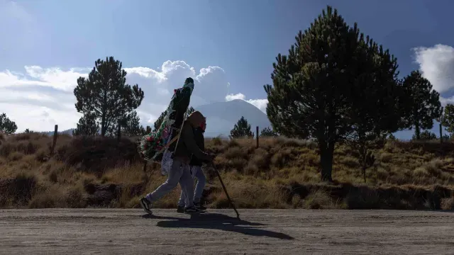 Dos peregrinos recorren la carretera del Paso de Cortés mientras cargan figuras de la Virgen de Guadalupe. Foto: N+