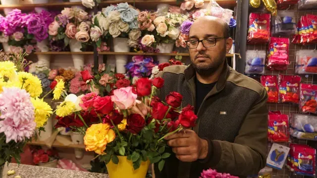 Un hombre hace un arreglo floral con rosas rojas y de varios colores