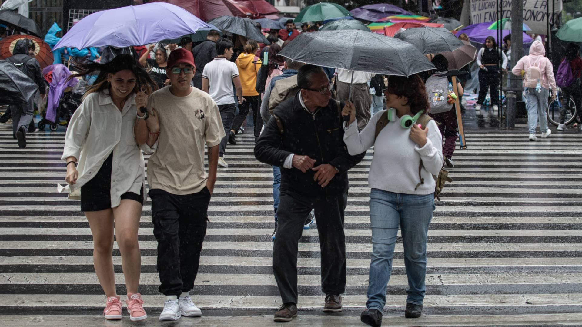 Personas usan paraguas para resguardarse de la lluvia