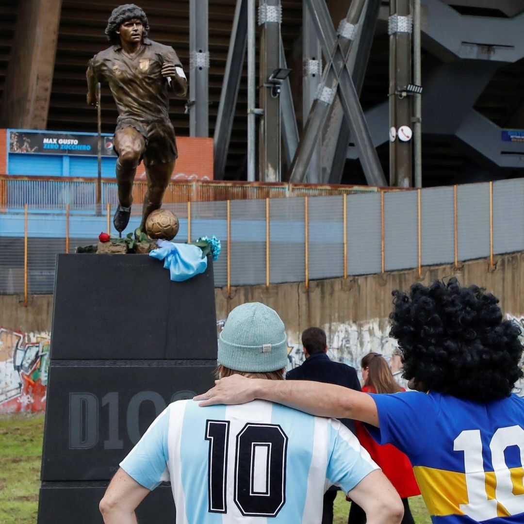 Seguidores de Maradona observan una estatua frente al estadio en Nápoles, Italia. Foto: Reuters