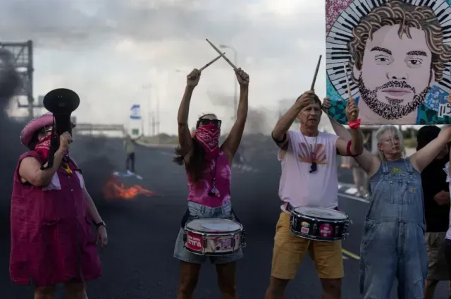 Cuatro personas con tambores y cárteles protestan para pedir un alto al fuego. Foto: Reuters