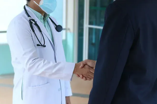 Un doctor saludando con la mano a un paciente